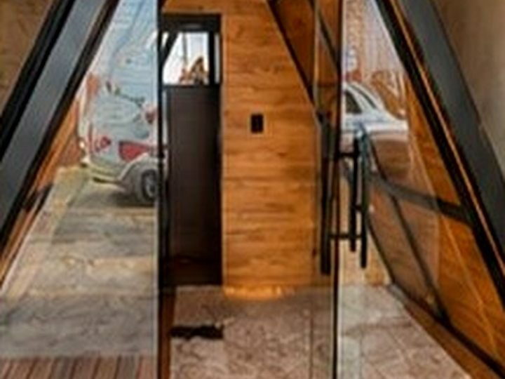 Entrada do chalé em vidro Blindex vista de dentro, com piso laminado
